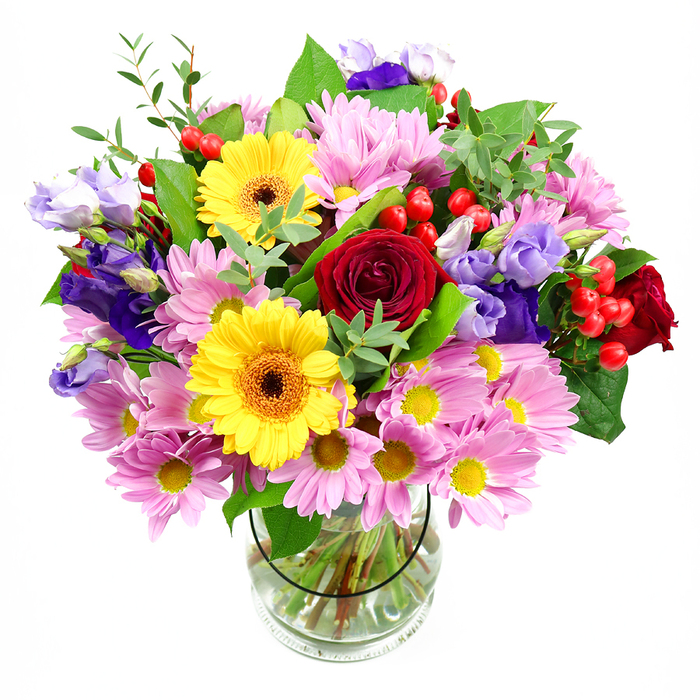In this elegant photograph, a mixed bouquet brimming with seasonal colour is arranged in a clear glass vase, standing alone against a crisp white backdrop so its texture and energy really stand out. At the centre, plush red roses unfurl in layered spirals, their velvety petals creating depth and a classic, romantic mood that would feel at home in any Camberwell townhouse or studio flat. Framing them, two bold yellow gerbera daisies with rich brown-orange centres provide bright contrast; their flat, daisy-like faces are wide open, projecting sunny optimism like the warm glow of shopfronts along Denmark Hill in the late afternoon. Around this dynamic pairing, plentiful pink daisies or chrysanthemums gather in clusters, each bloom made up of lots of slim petals around a soft yellow centre, giving the bouquet a cloud-like fullness and a relaxed, informal charm. Slender stems of lisianthus in shades of purple and lavender weave softly through the arrangement, their bell-shaped buds and partially opened flowers adding cool-toned sophistication and gentle movement. Between these, shiny red hypericum berries appear in small groups, perched like tiny ornaments and adding a contemporary, tactile edge. The whole posy is supported by an assortment of leafy greens-broad, glossy leaves that cradle the blossoms and finer, lighter green sprigs that spill slightly over the rim of the vase, suggesting a freshly gathered feel, as if just brought in from a stroll near Burgess Park. Through the transparent vase, neatly cut stems are visible, standing straight in crystal-clear water, underscoring the careful, professional conditioning behind the design. This bouquet's bright yet harmonious colours and inviting textures make it ideal for birthdays, thank-you gestures, or simply lifting the mood in a Camberwell living room or office, filling the space with the quiet joy of well-chosen flowers.